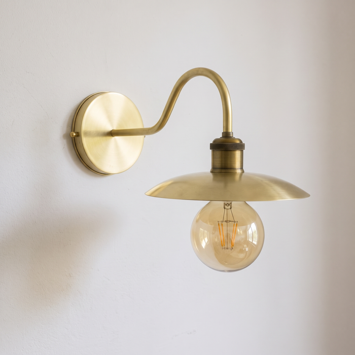 Brushed brass gooseneck wall sconce with small saucer shade and globe bulb