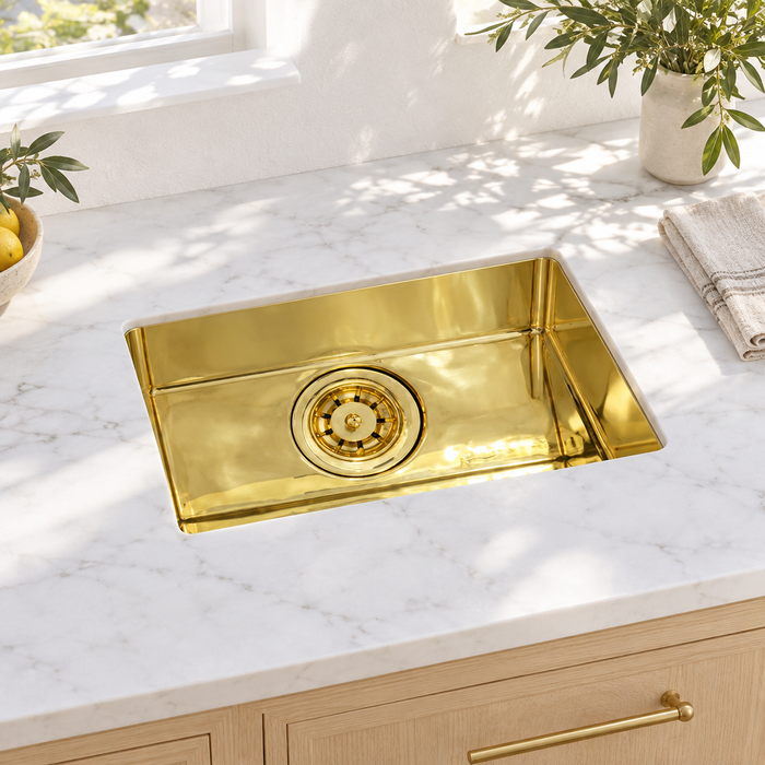 Compact rectangular brass undermount sink in a sunlit white marble kitchen