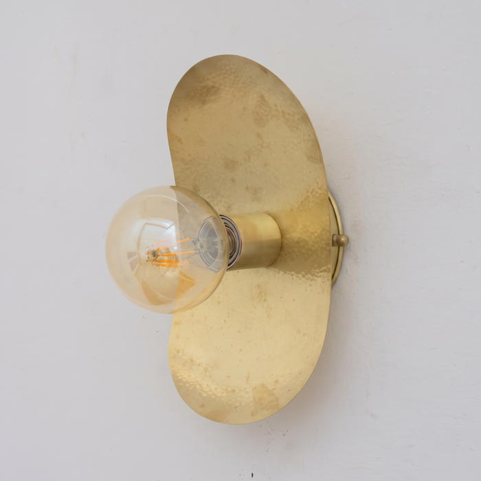 Hammered unlacquered brass oval plate wall sconce with globe bulb