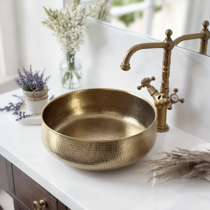 Brass vessel sink on a white marble bathroom vanity with a brass tap