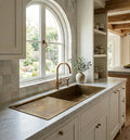 Aged brass kitchen sink with drainboard under an arched window