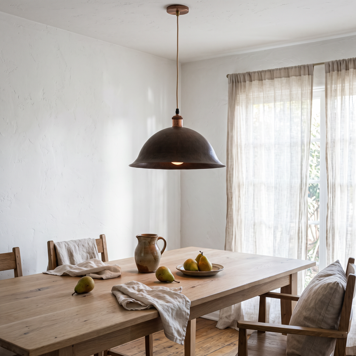 Aged copper bell dome pendant light over a white oak dining table