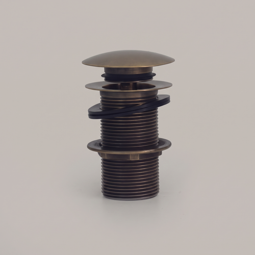 Antique brass push pop-up sink drain with domed cap on a light background