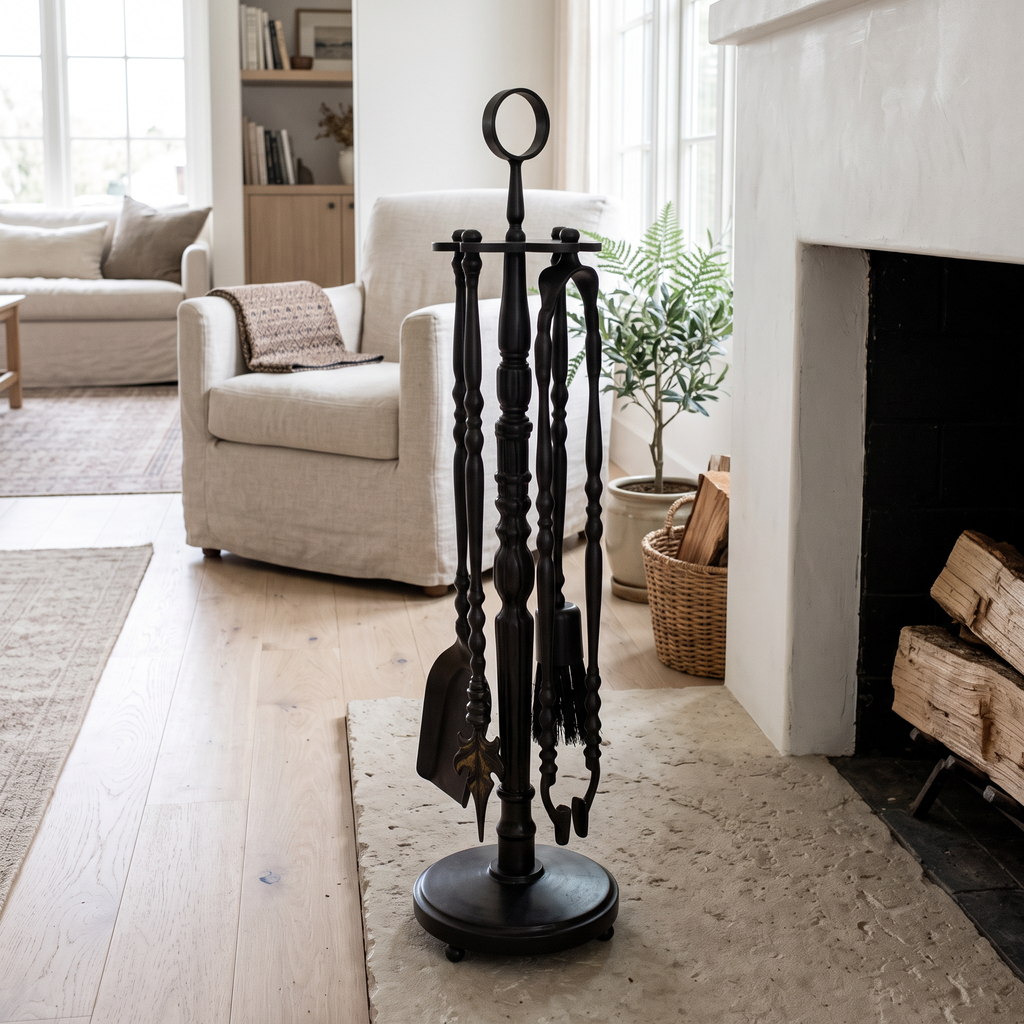 Black brass fireplace tool set on a round stand on a limestone hearth in a bright living room