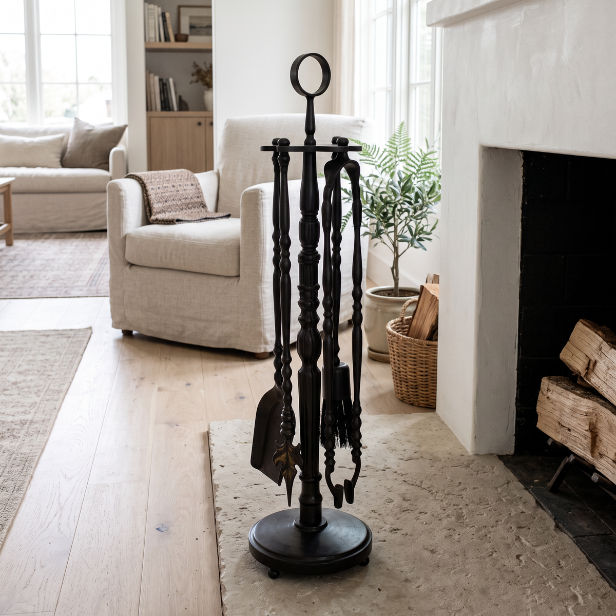 Black brass fireplace tool set on a round stand on a limestone hearth in a bright living room