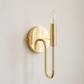 Unlacquered brass curved arm candle wall sconce on a light background