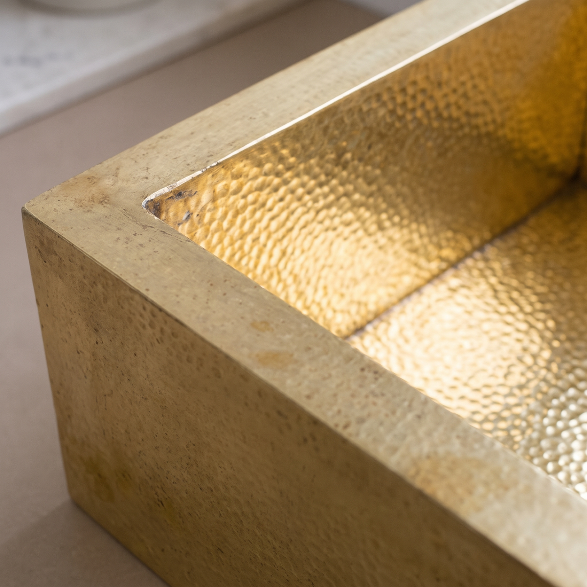 Close-up of hammered brass basin and thick matte brass wall