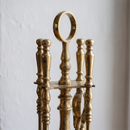 Close-up of the ring handle and turned baluster handles of the brass fireplace tools