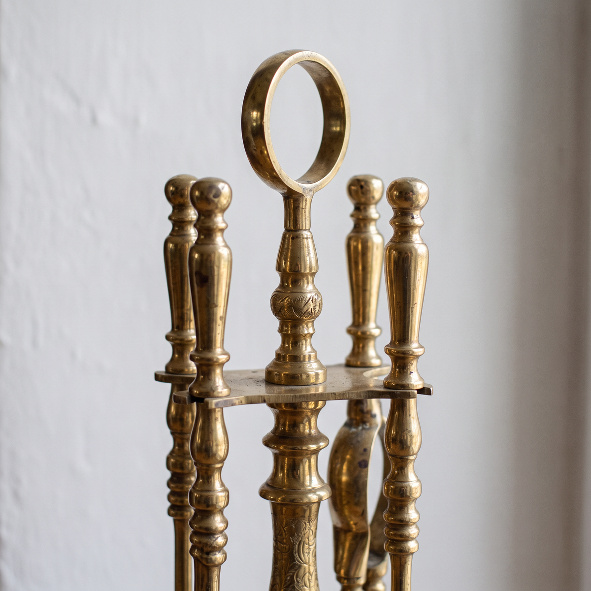 Close-up of the ring handle and turned baluster handles of the brass fireplace tools