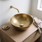 Brass push-up drain in a hammered brass vessel sink on a white oak vanity