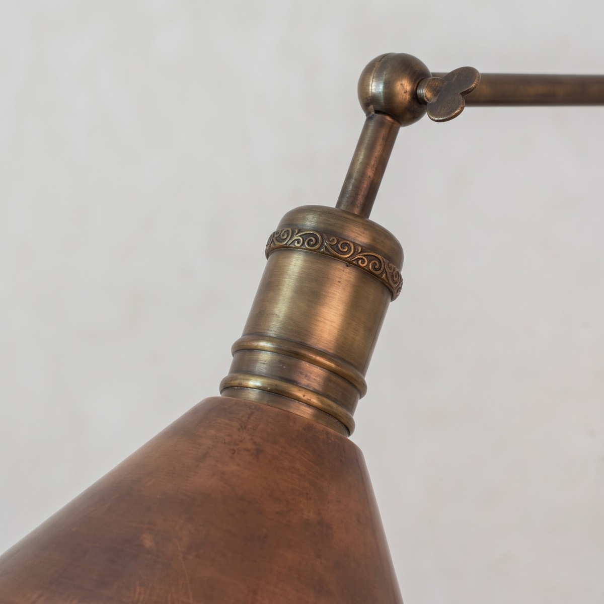 Close-up of the scrolled brass socket band, ball joint and aged copper shade