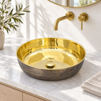 Bronze and brass round vessel sink on a sunlit white marble bathroom vanity