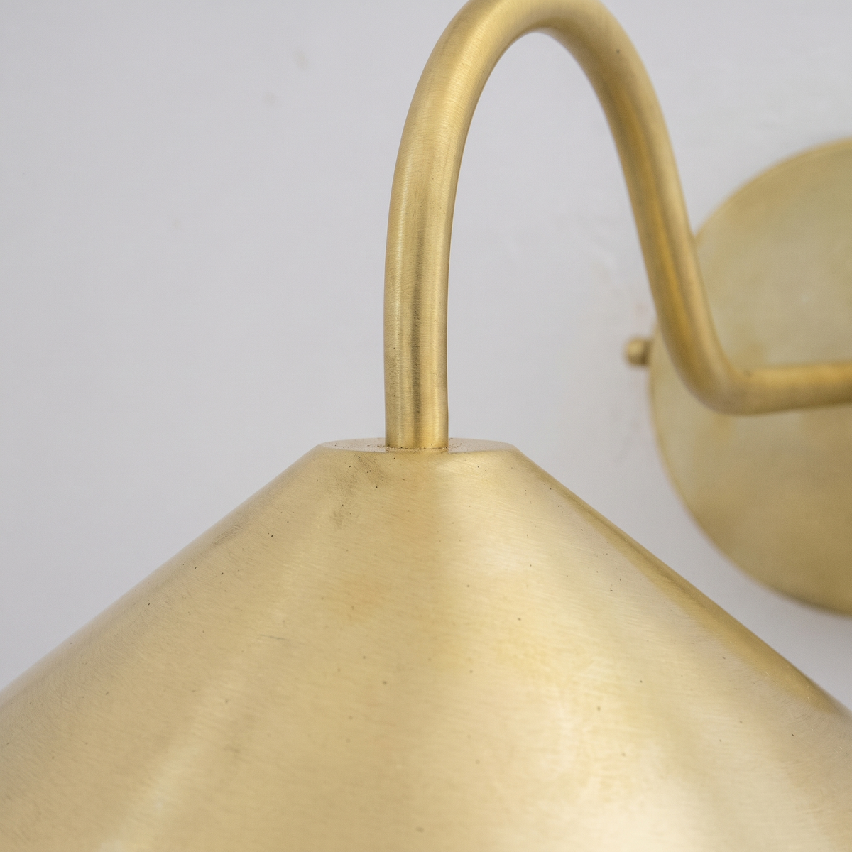 Close-up of the brushed brass cone shade and curved arm