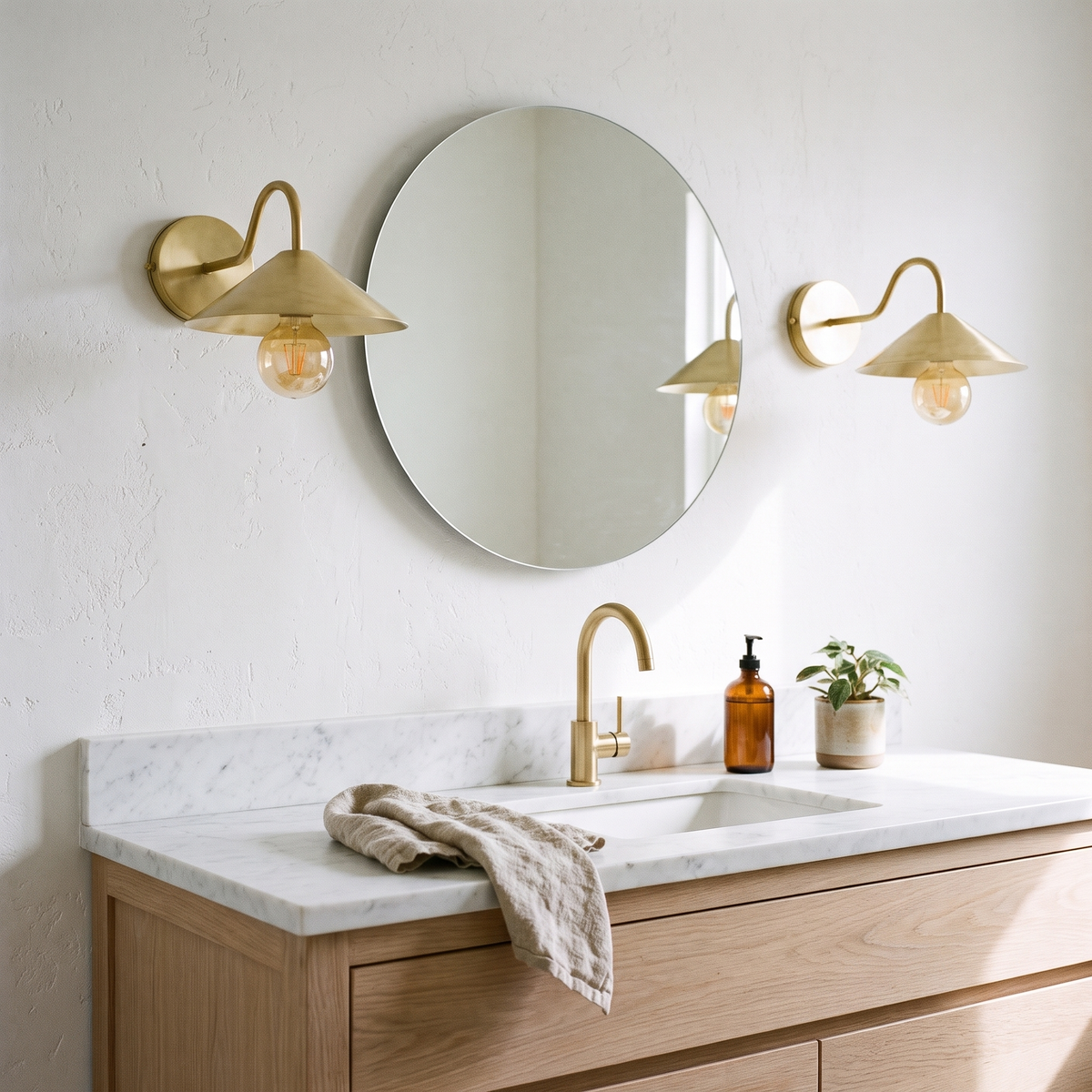 Pair of brushed brass cone shade sconces either side of a bathroom mirror