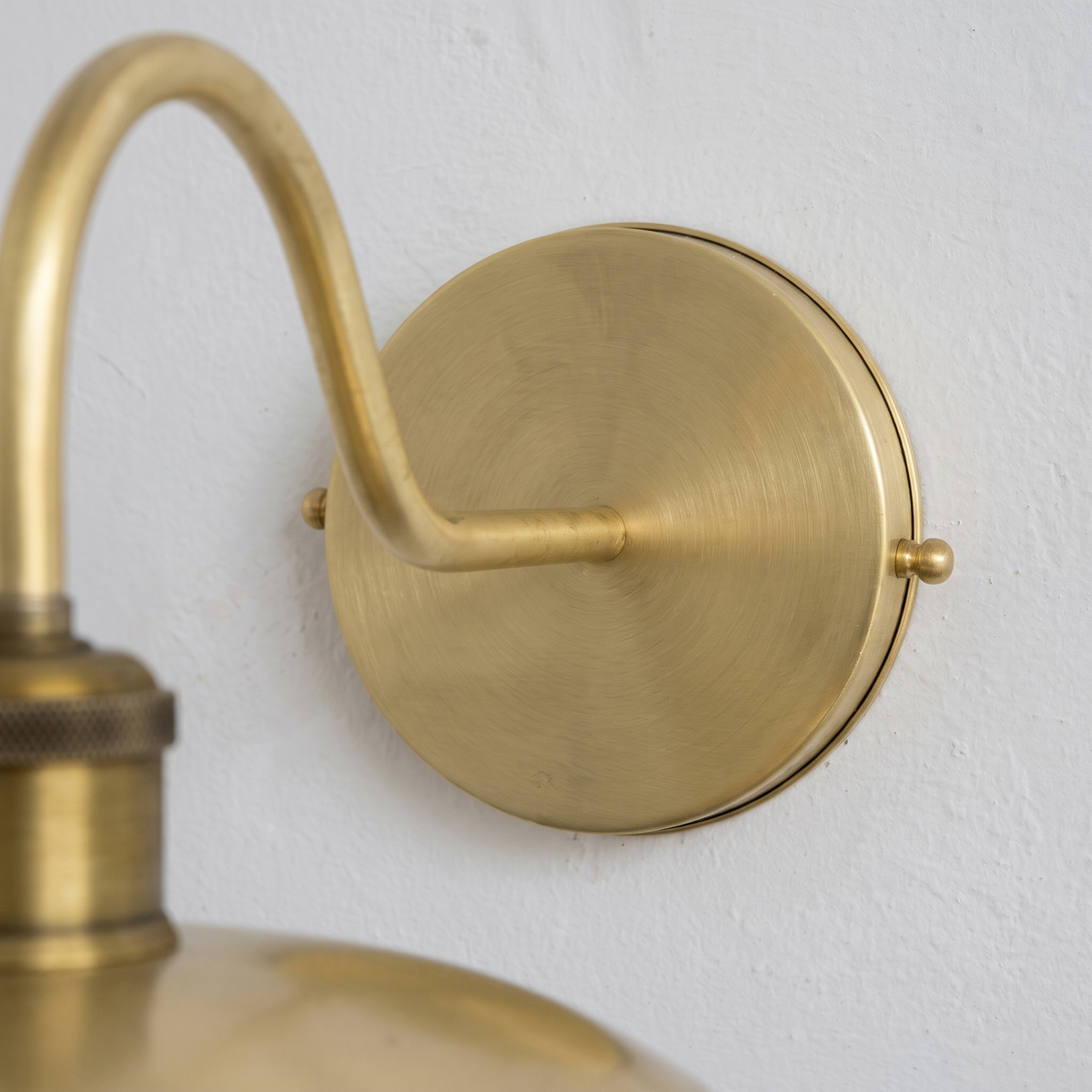 Close-up of the brushed brass round backplate and gooseneck arm