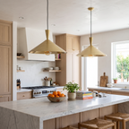 Two brushed brass wide cone pendant lights over a white marble kitchen island