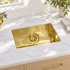 Compact rectangular brass undermount sink in a sunlit white marble kitchen