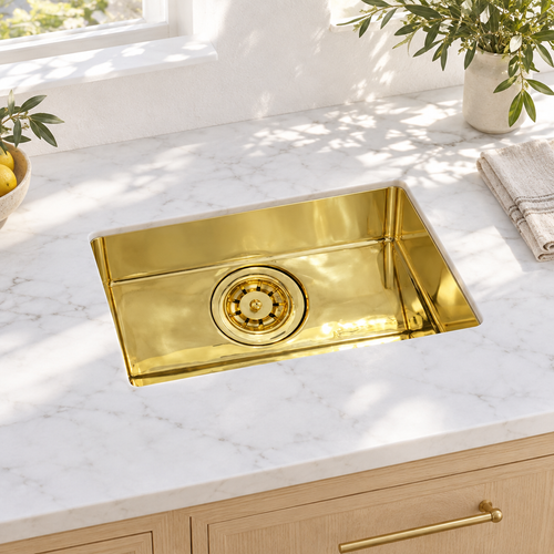 Compact rectangular brass undermount sink in a sunlit white marble kitchen