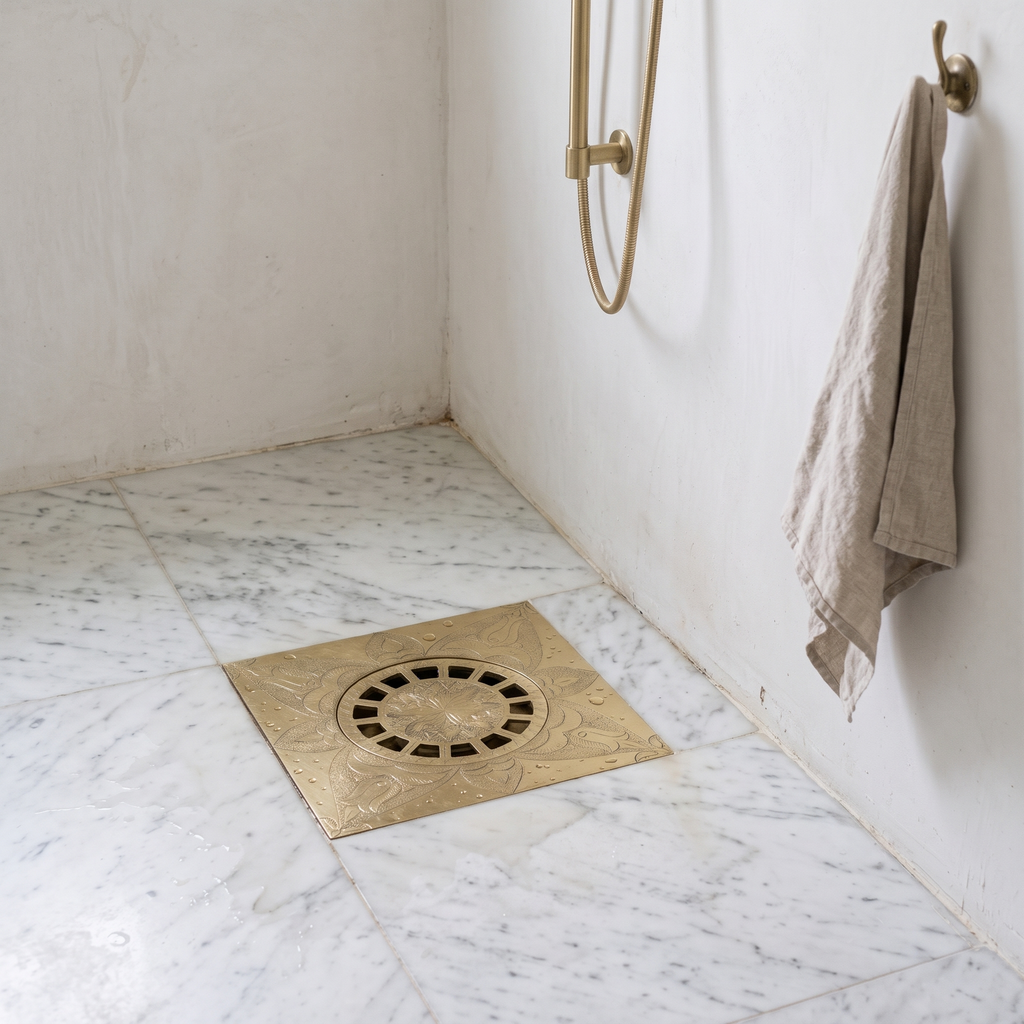 Engraved brass floor drain set in a honed marble shower floor