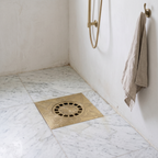 Engraved brass floor drain set in a honed marble shower floor