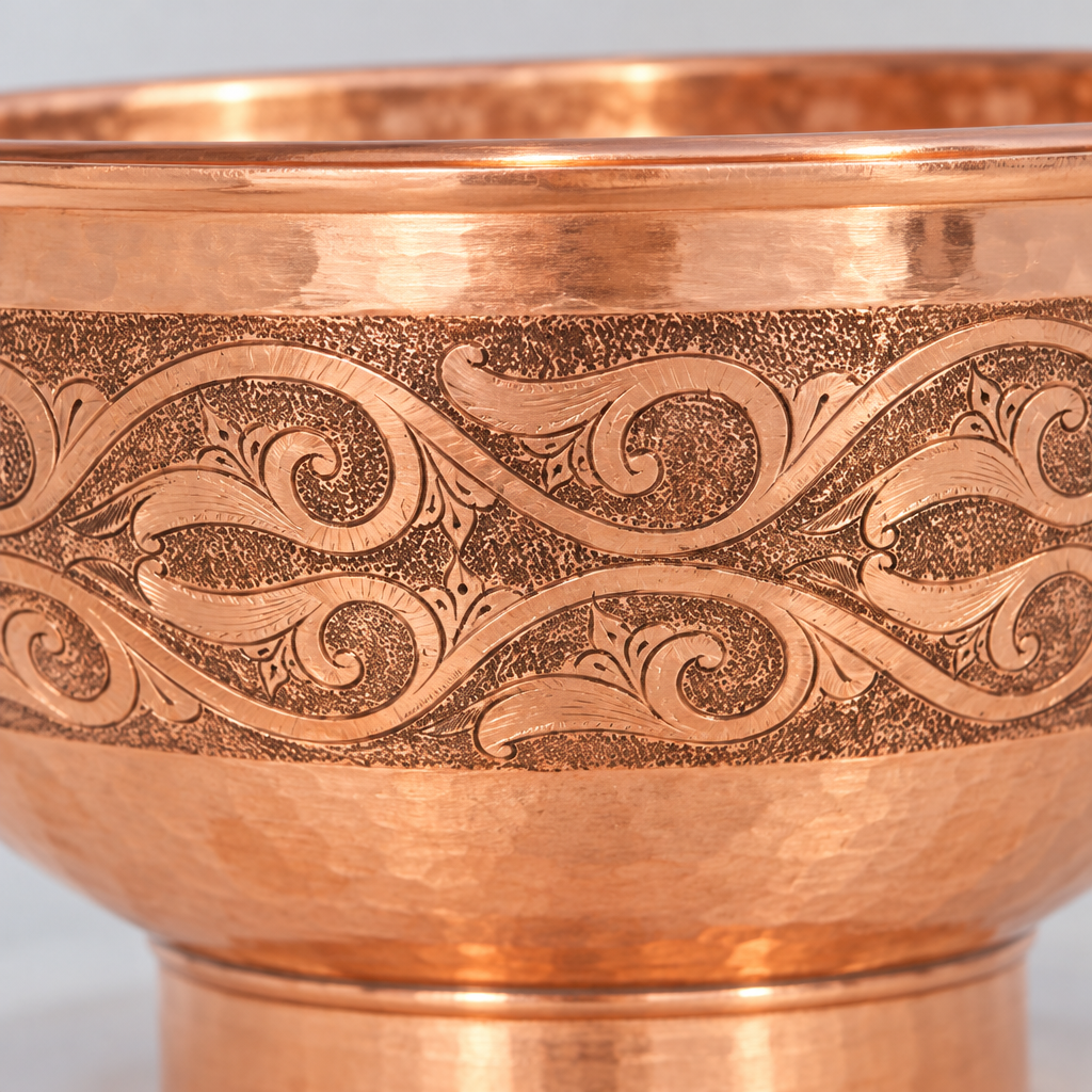 Close-up of the engraved copper pedestal vessel sink showing the finish