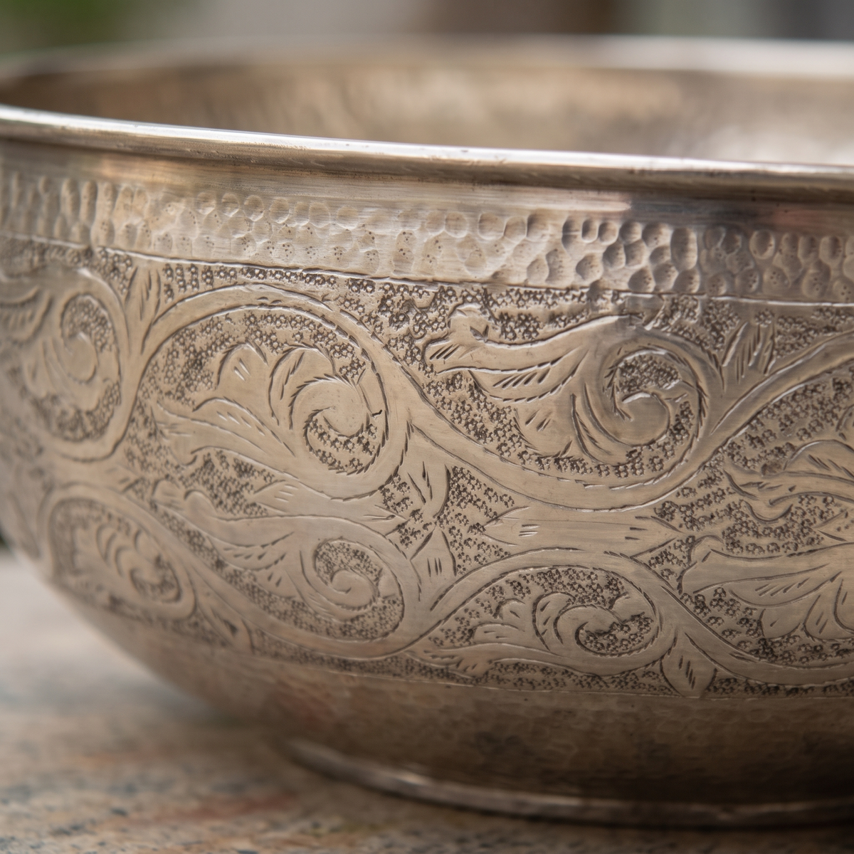 Close-up of the hand-engraved scrolling vine pattern and hammered band on a German silver bowl