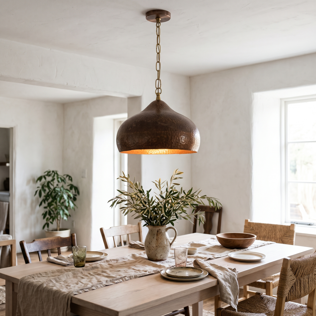 Antique copper bell pendant on a brass chain over a white oak dining table