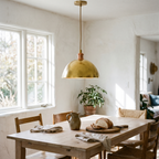 Hammered brass dome pendant light over a white oak dining table