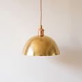 Hammered brass dome pendant light with copper-toned socket cup on a light background