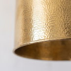 Hand-hammered texture and rolled edge of the brass drum pendant