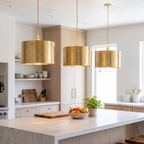 Three hammered brass drum pendant lights over a white marble kitchen island