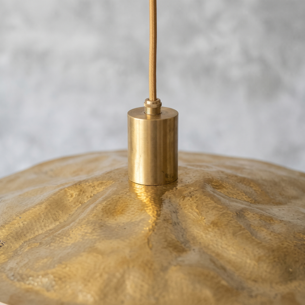 Close-up of the rippled hand-hammered brass disc and plain brass socket cover