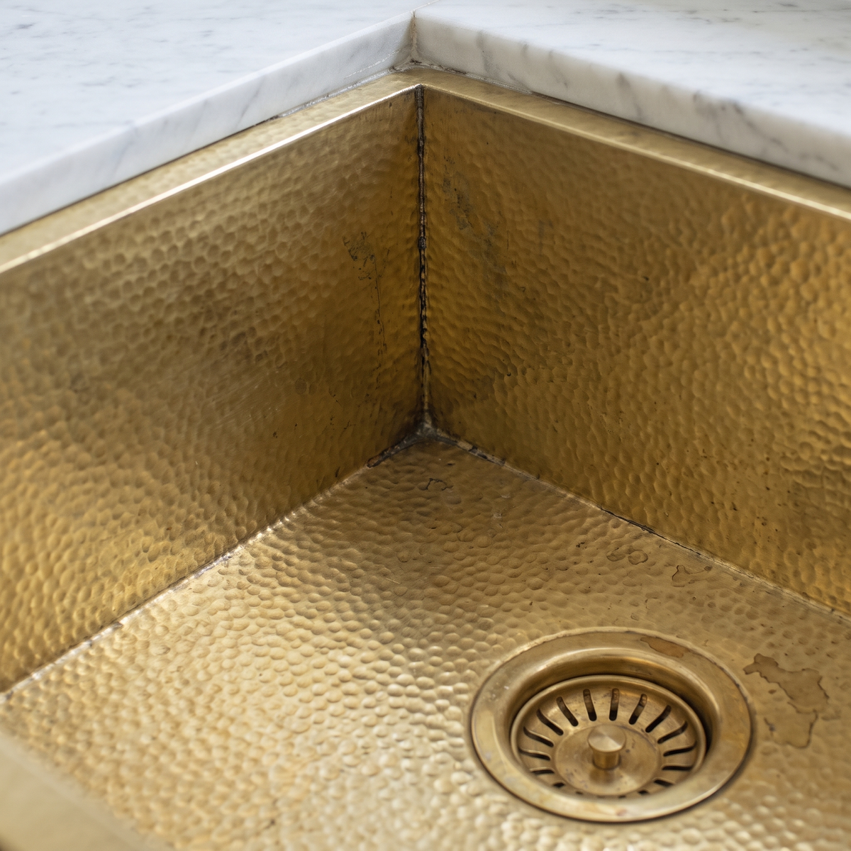 Close-up of hammered brass texture, sealed corner and brass basket strainer