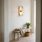 Hammered brass oval plate wall sconce above a white oak hallway bench