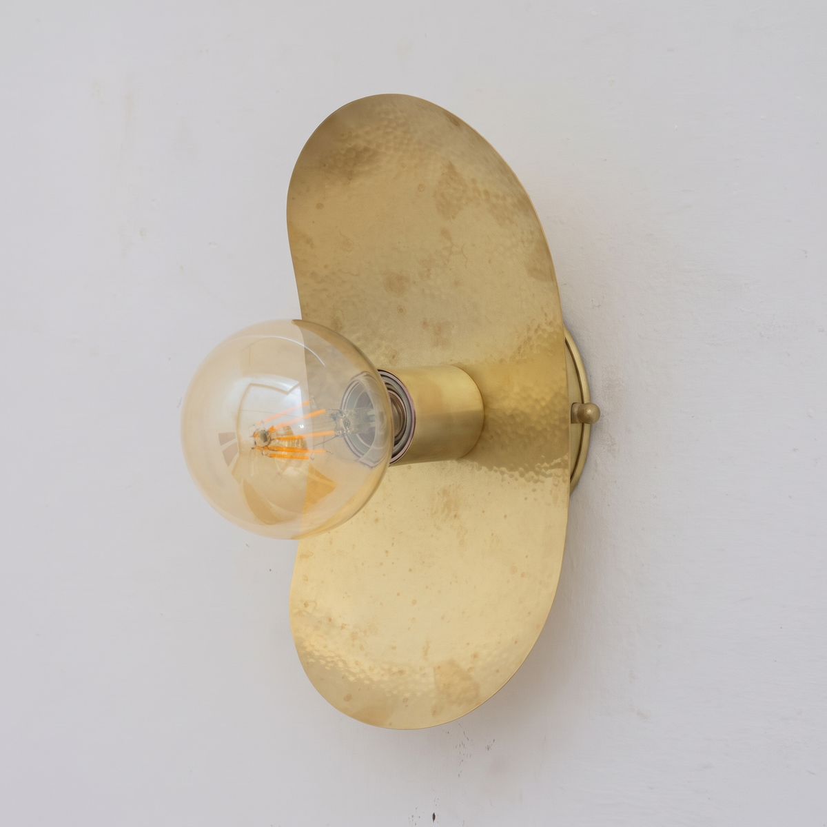 Hammered unlacquered brass oval plate wall sconce with globe bulb