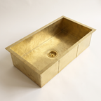 Hand-hammered rectangular brass kitchen sink with brass basket strainer