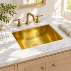 Hammered brass rectangular sink under a sunlit white marble vanity top