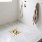 Hammered brass floor drain set in a honed marble shower floor