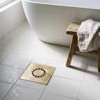 Hammered brass floor drain in a white tiled wet room near a bathtub