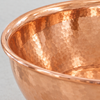 Close-up of the hammered copper pedestal bowl vessel sink showing the finish