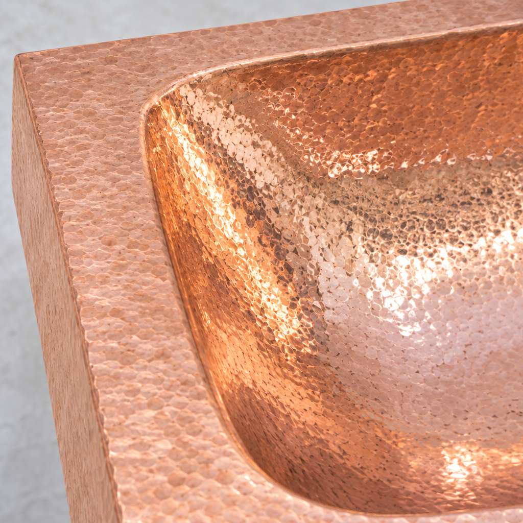 Close-up of the hand-hammered copper border curving into the basin