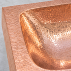 Close-up of the hand-hammered copper border curving into the basin