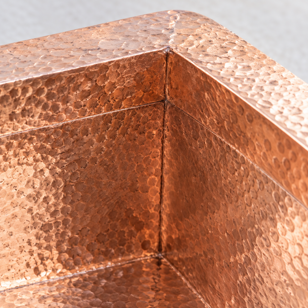 Close-up of a hand-hammered inside corner and flange of the copper sink