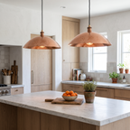 Two hammered copper wide dome pendant lights over a white marble kitchen island