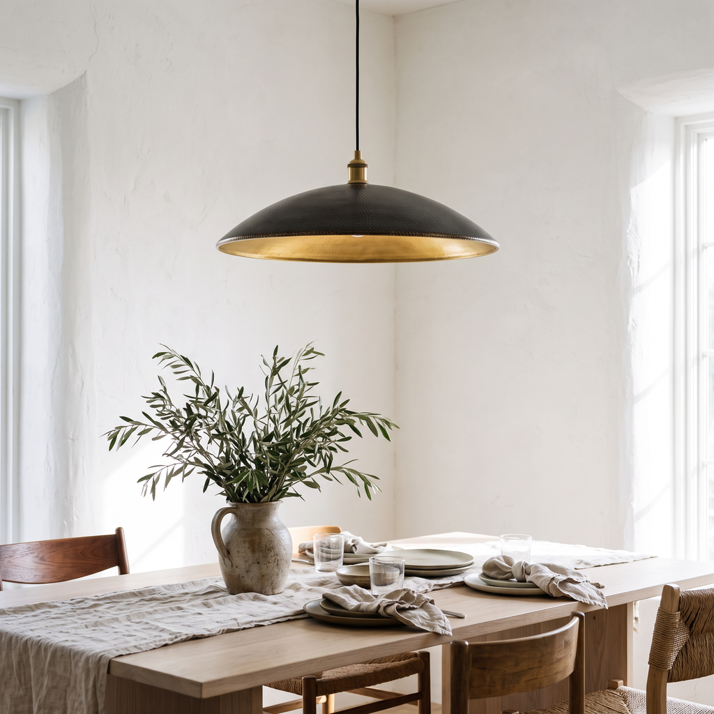 Hammered dark bronze saucer pendant over a white oak dining table