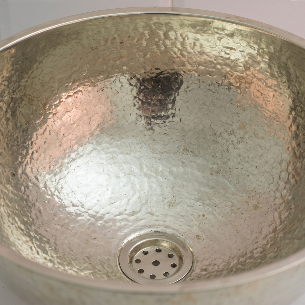 Close-up of the even hand-hammered dimples and drain inside a German silver bowl