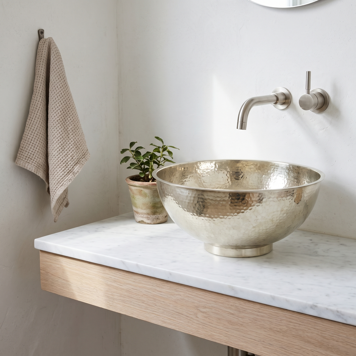 German silver bowl vessel sink on a floating white oak vanity in a bright powder room