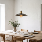 Hammered grey bronze saucer pendant light over a white oak dining table