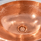 Hammered Oval Copper Vessel Sink close-up of the hammered copper and drain