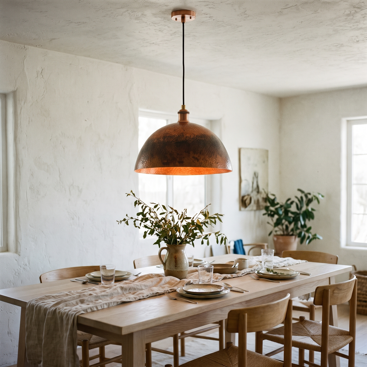 Oxidized copper dome pendant light over a white oak dining table